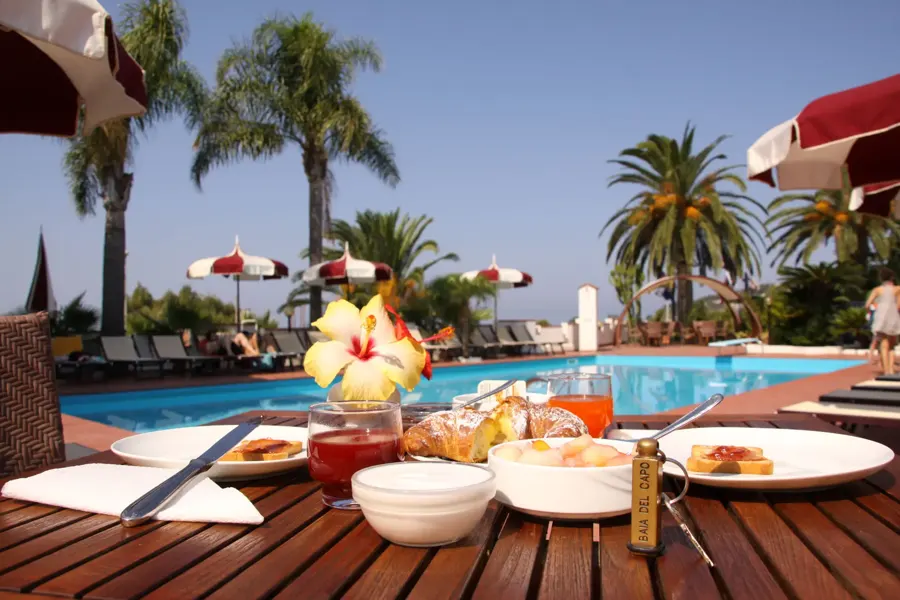 Frühstückstisch am Hotelpool mit Palmen